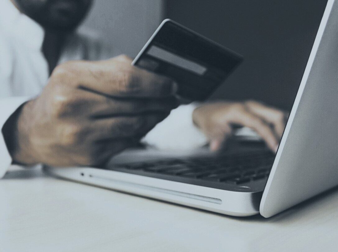 Man holding a credit card in front of a laptop